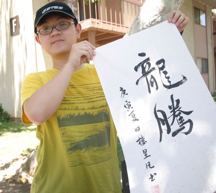 Logan Lou, 15, in front of University Housing with the words "Flying Dragon" in Chinese calligraphy that he created with ink on rice paper.