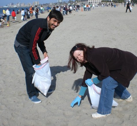 Cheryl McKnight, director of the Center for Service Learning, Internships, & Civic Engagement and Honors Program student Adrian Villarruel help clean up the beach
