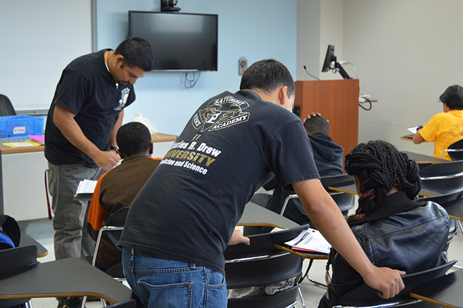 (l to r) Ronald Gonzalez and Hector Meza-Lopez work with Saturday Science Academy students on math problems.