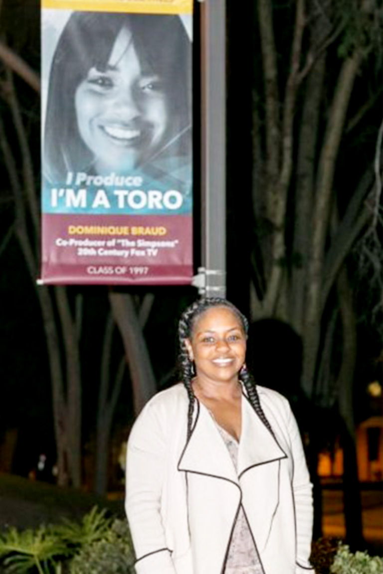 Dominique Braud stand by her alumni banner