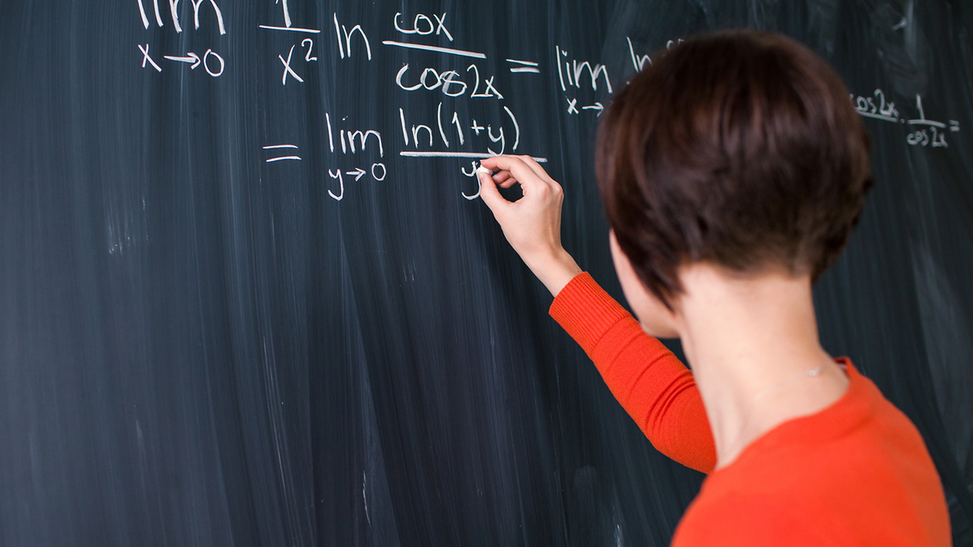 stock photo of student writing math equations on chalkboard