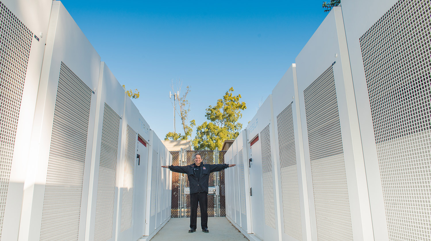 Kenny Seeton, Central Plant/energy manager at CSUDH, stands among 20 Tesla battery banks installed on campus to help reduce the university's impact on the local power grid.