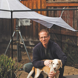 Research volunteer Eric Keller and his dog sit in front of a backyard insect trap.