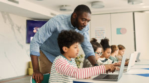 Teacher instructing schoolchildren at computers