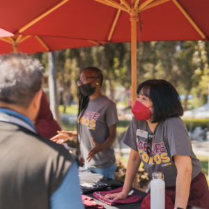 Two CSUDH staff members greet individuals at one of the Toro Admit Day Resource Fair tables.