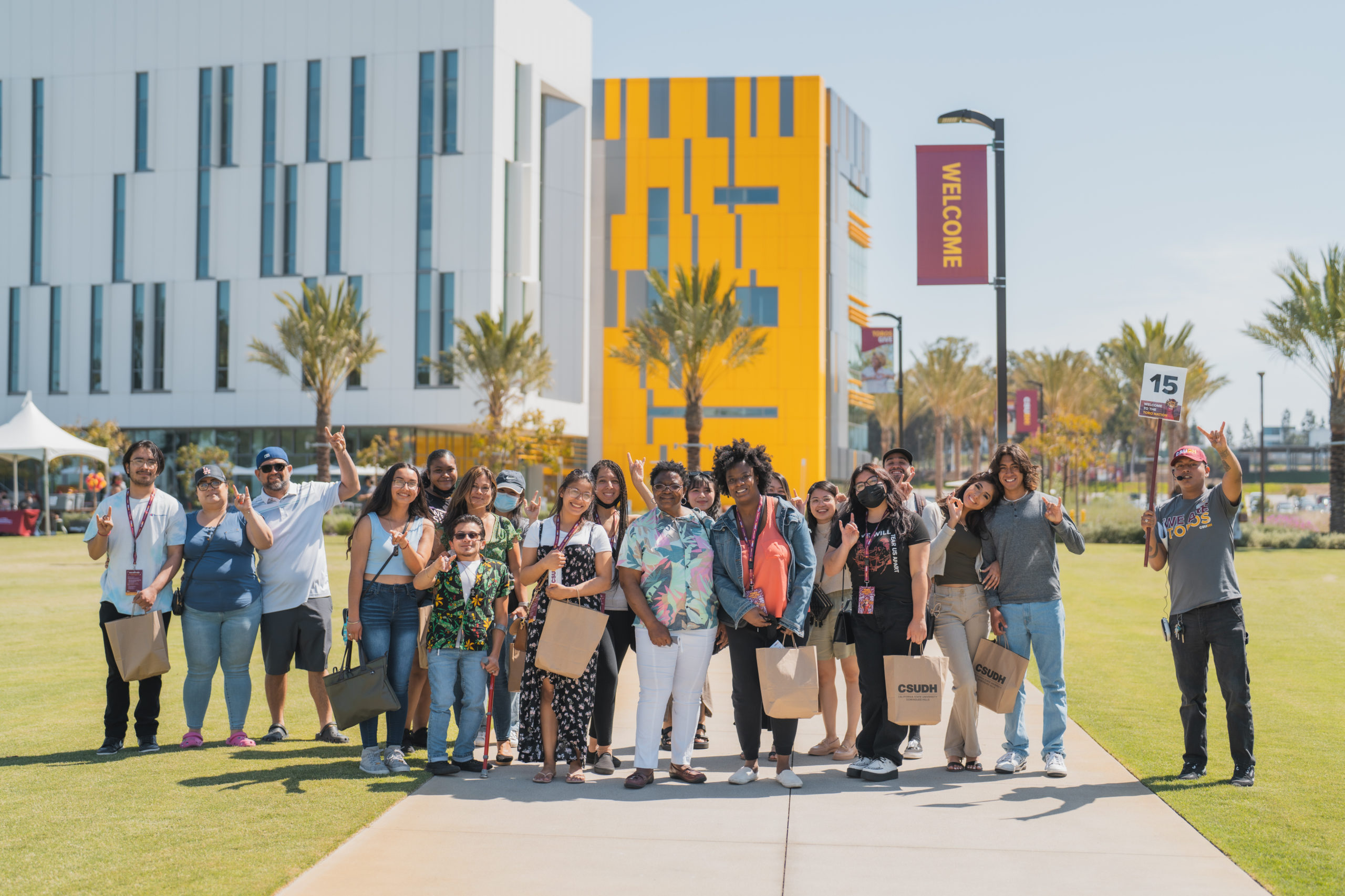 20 people on a tour of the CSUDH campus pose for a group photo in front of the Innovation and Instruction building.