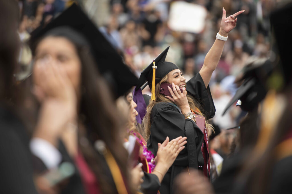 A graduate waving in the crowd