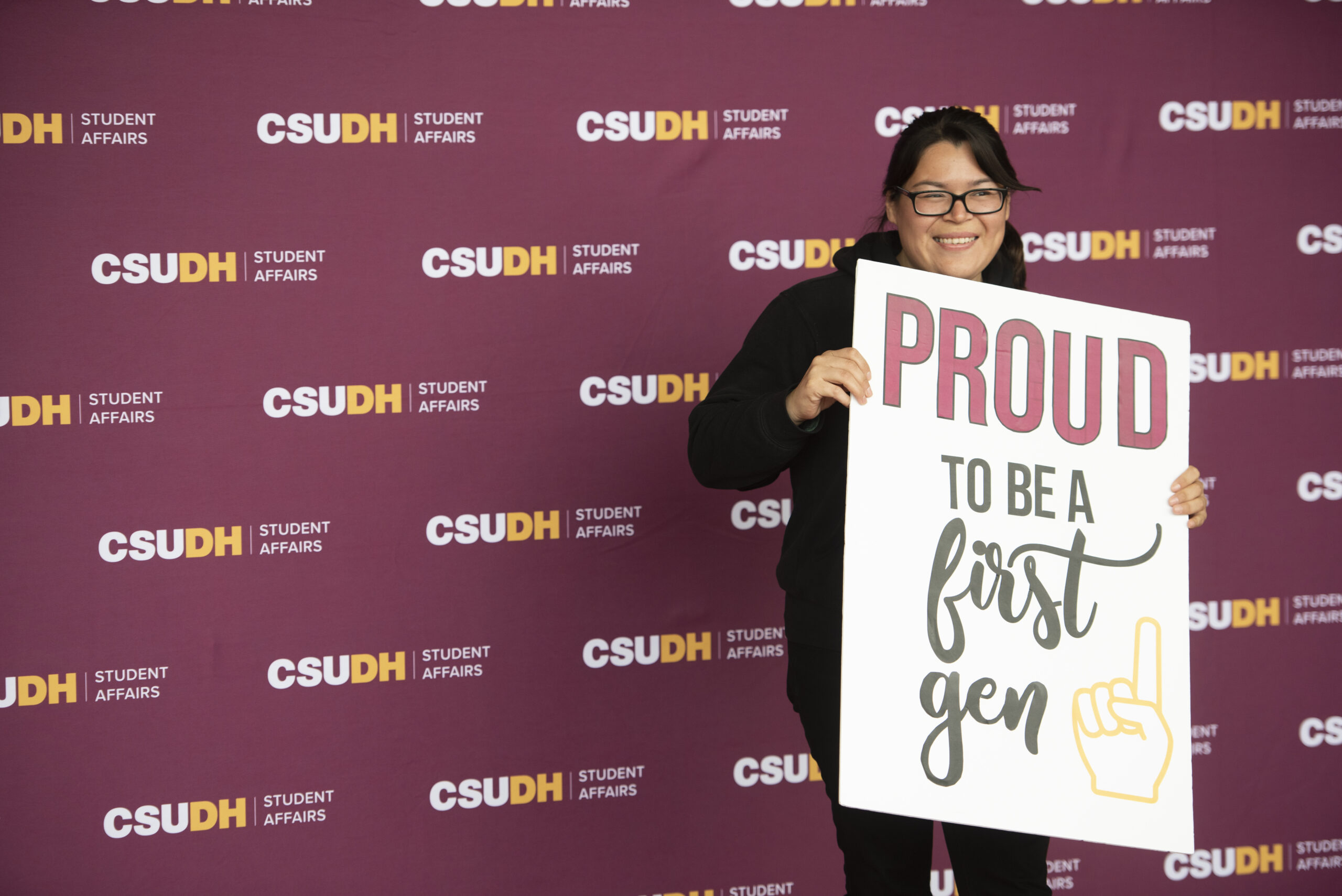 Student holding proud to be a first Gen sign