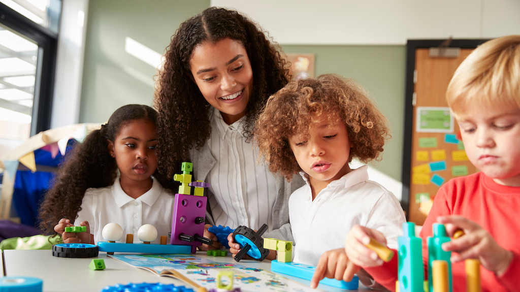 Teacher doing building activity with young children.