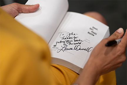 Closeup of Laura Warrell signing a copy of her debut novel. 