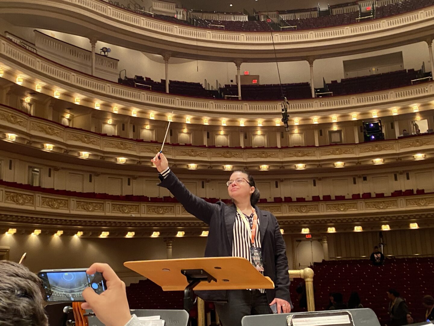 Amanda Chavez with her baton in the air inside Carnegie Hall