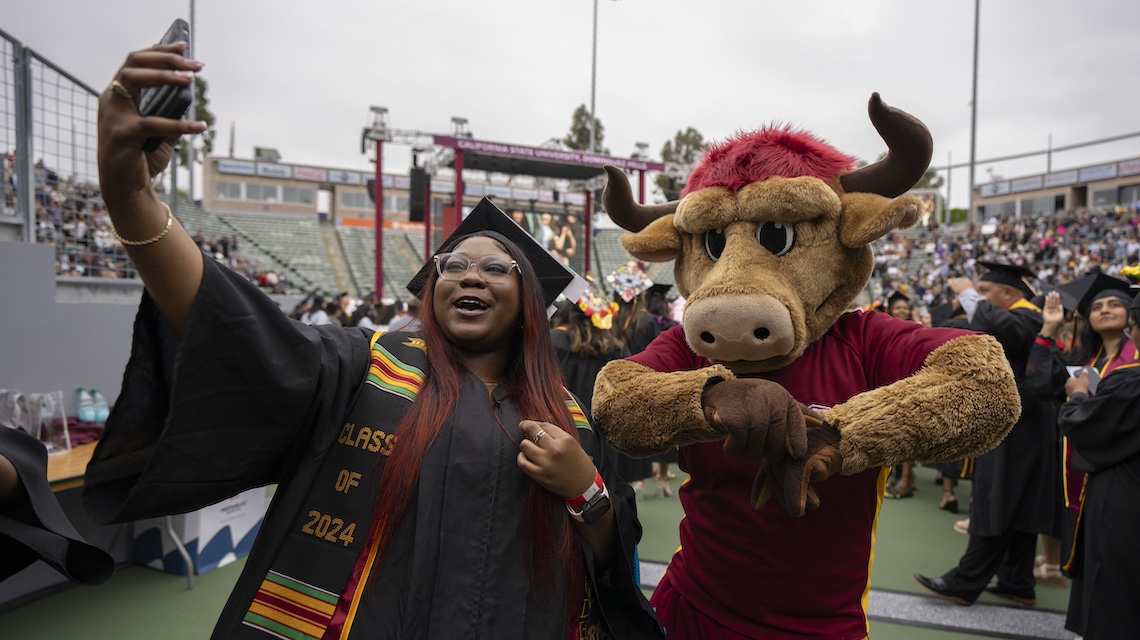 Graduate taking a selfie with Teddy the Toro