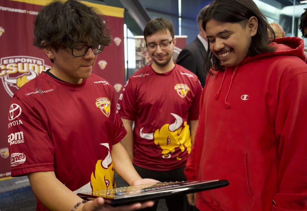 Esports team members look at their winning plaque