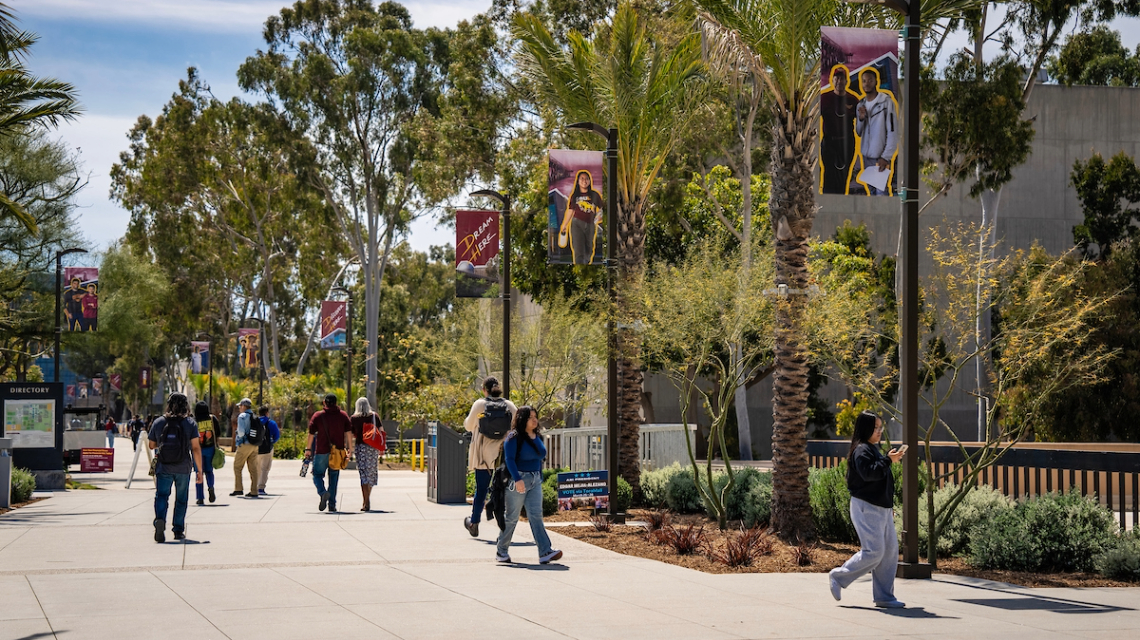 Students walking on a campus walkway underneath "Dream Here" banners