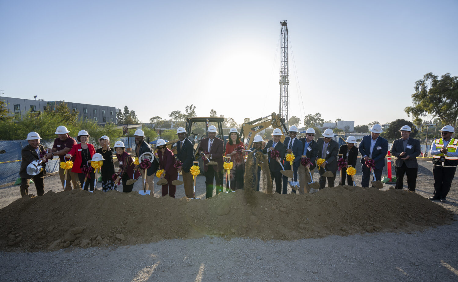 Large group posing with shovels at dig site