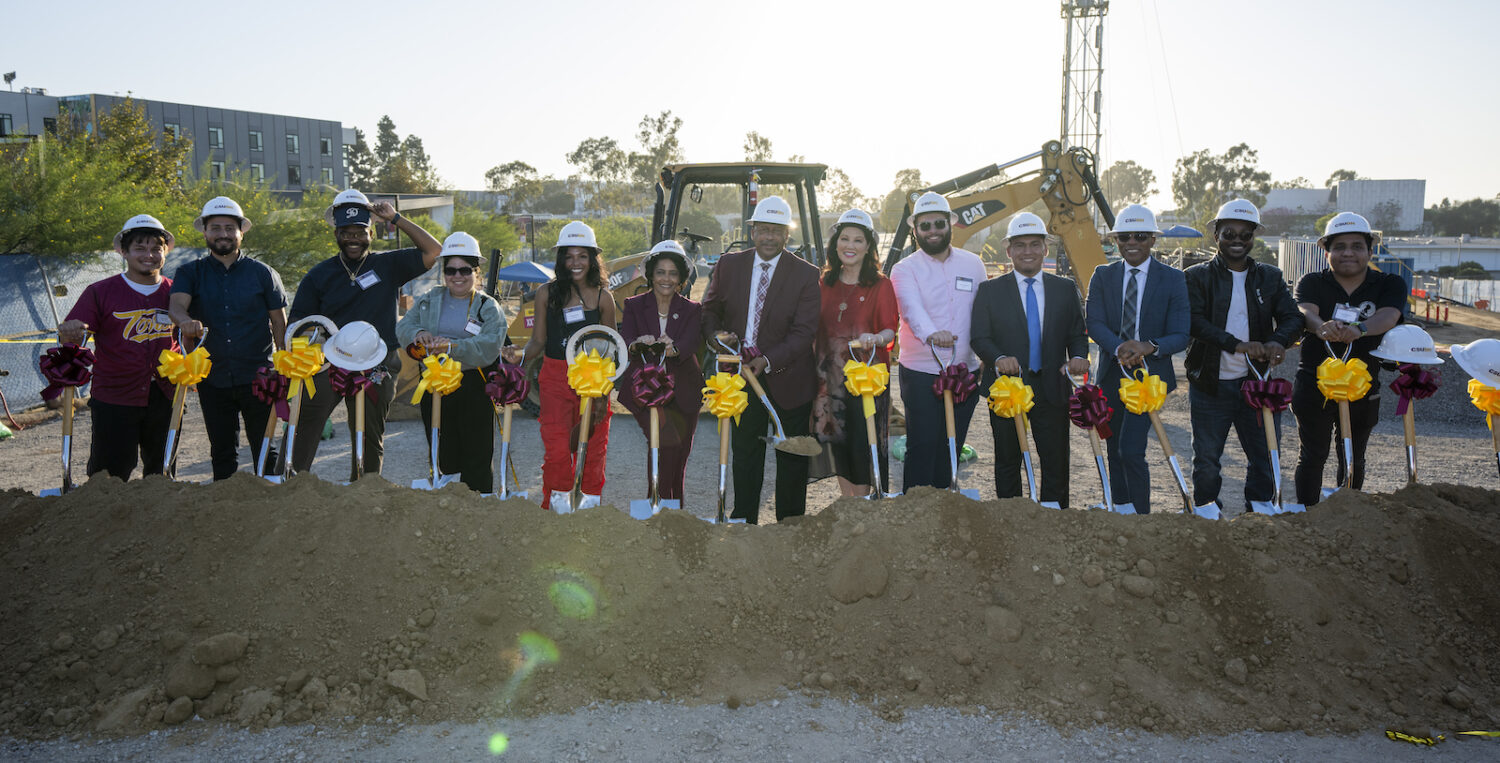 Large group posing with shovels at dig site