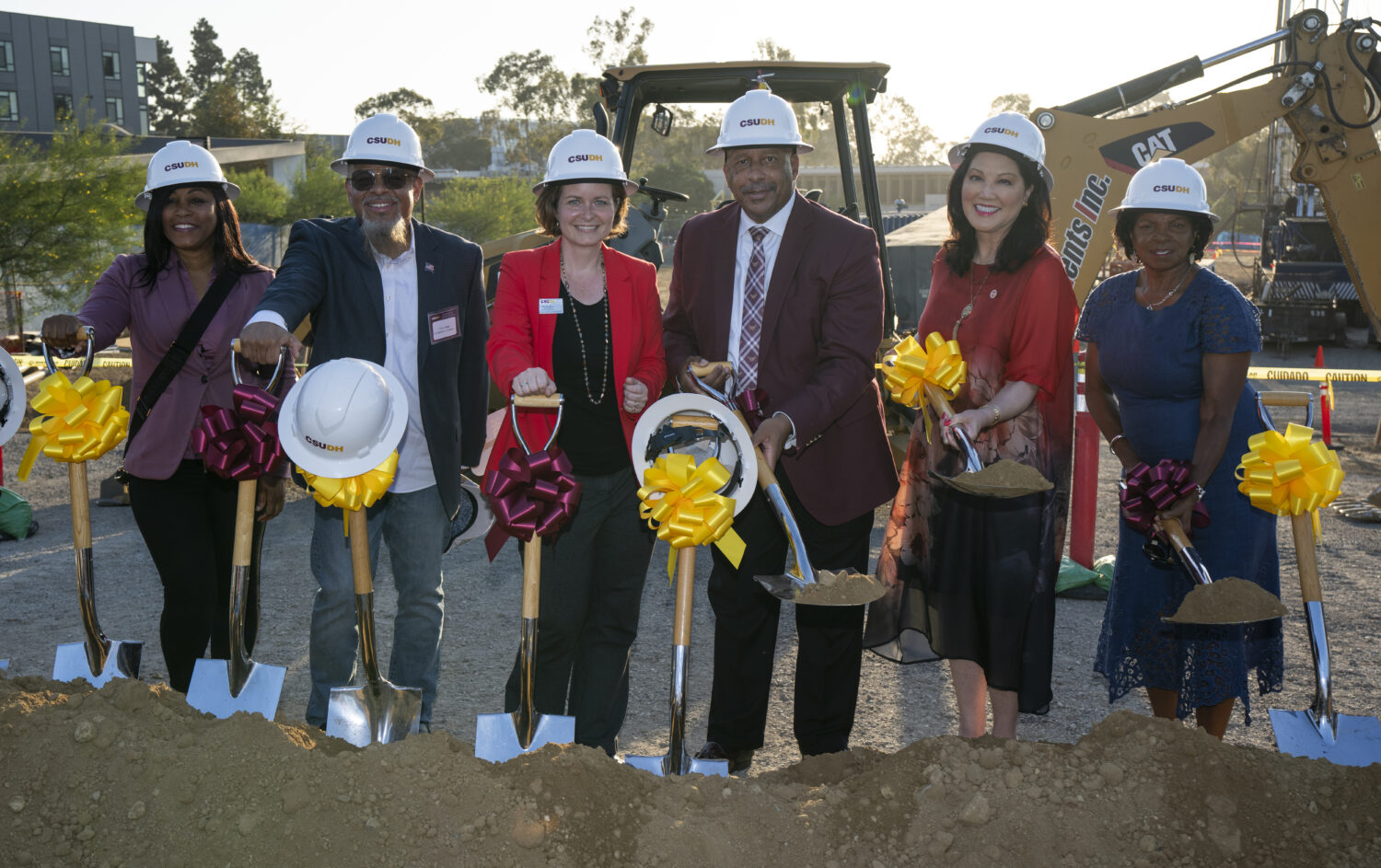 Group posing with shovels at dig site