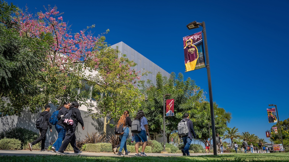 Students walking on campus underneath CSUDH banners