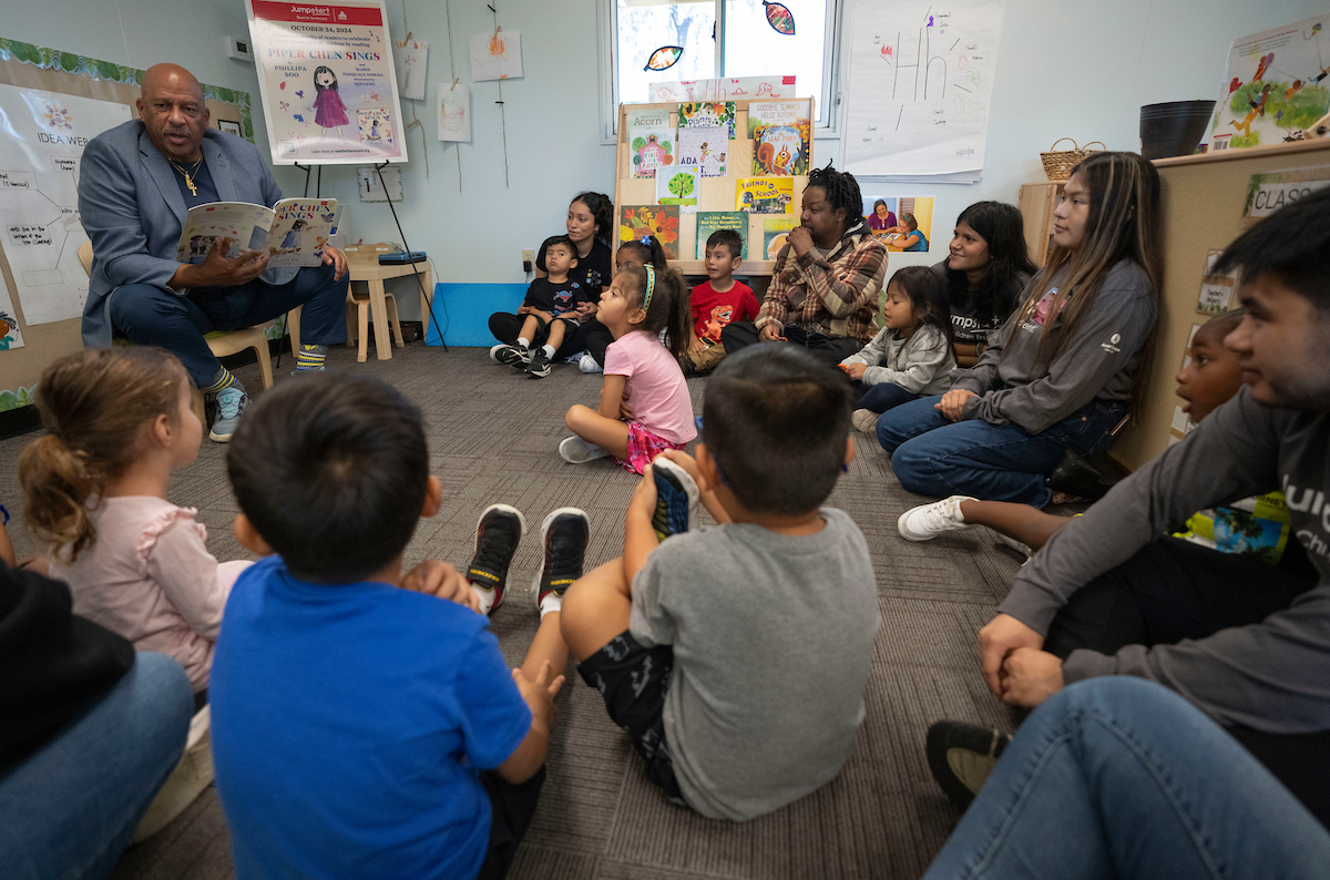 President Parham reading a book to seated children