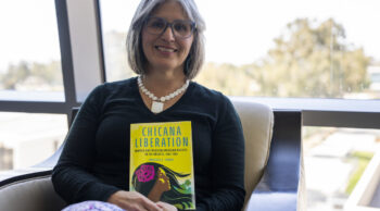 Marisela Chávez holding her book, Chicana Liberation.