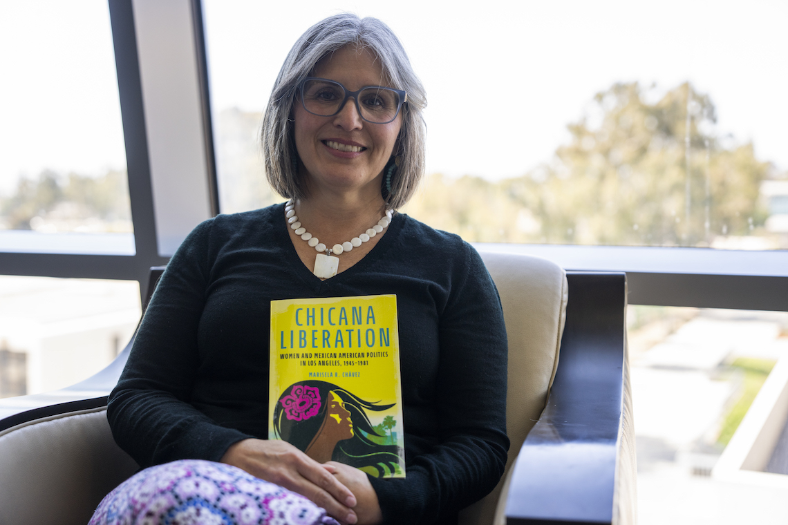 Marisela Chávez holding her book, Chicana Liberation.