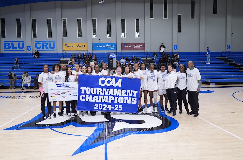 The Toro women's basketball team holding the CCAA Tournament Champions 2024-25 banner