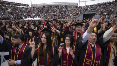 Graduates making the Toro hand sign and cheering during Commencement