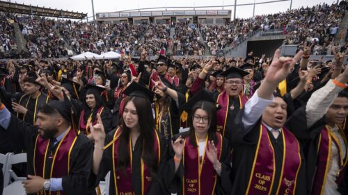 Graduates making the Toro hand sign and cheering during Commencement
