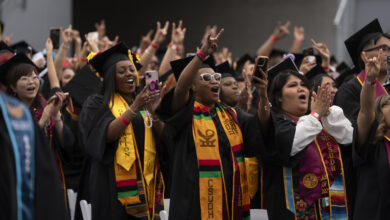 Students in regalia making Toro hand signals at Commencement