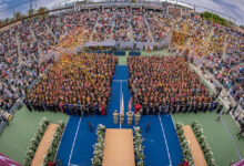 A curved aerial view of seated graduates and guests at Commencement.