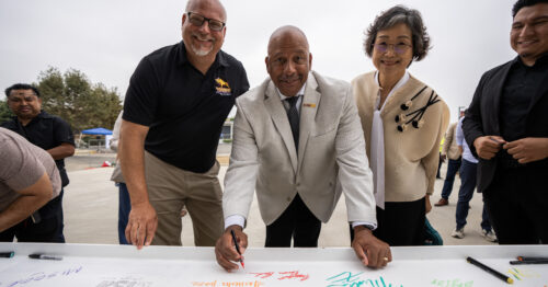 President Parham and university leaders signing a metal beam