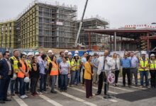 Group of university leaders and construction workers on campus building site