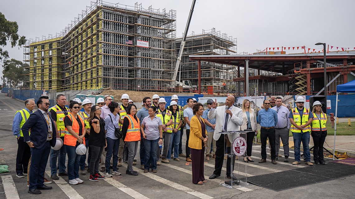 Group of university leaders and construction workers on campus building site