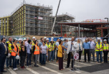 Group of university leaders and construction workers on campus building site