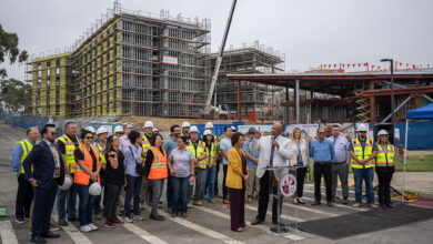 Group of university leaders and construction workers on campus building site