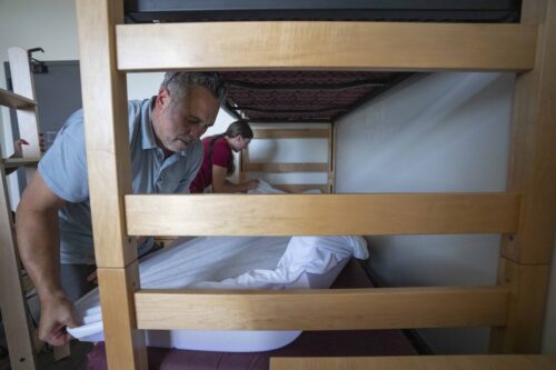 Family putting sheets on a bed in the residence hall