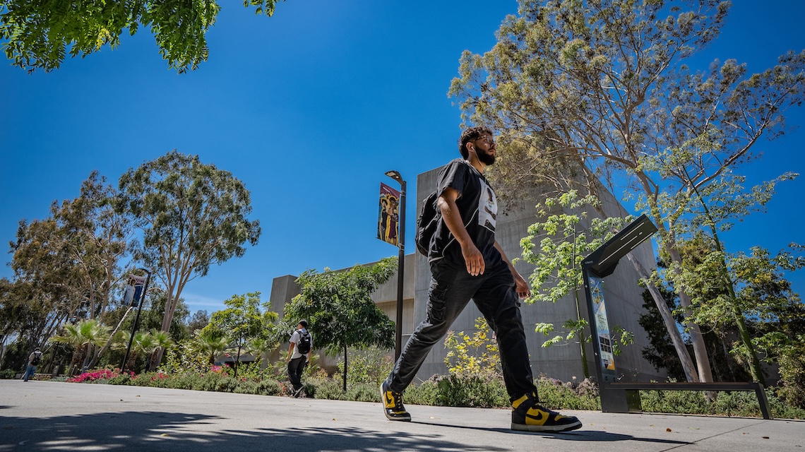 Student walking on campus walkway.