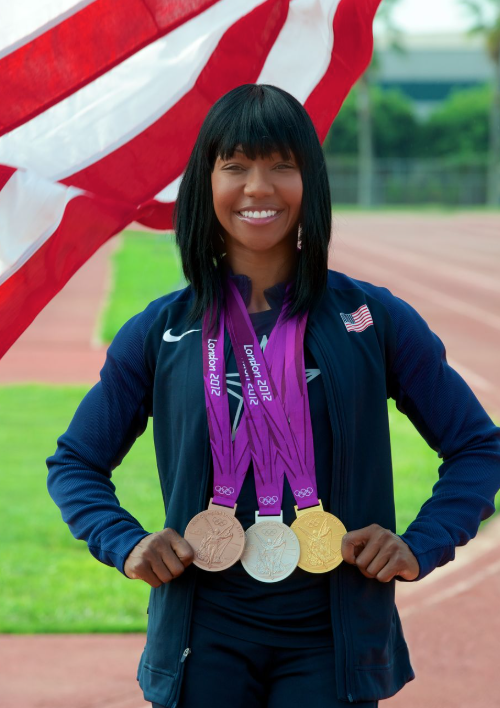 Jeter, with medals, posing on CSUDH track with American flag in background