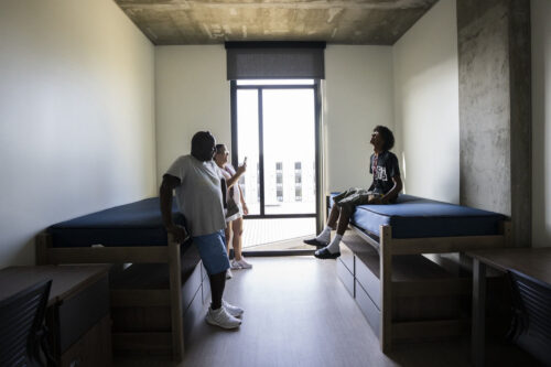 A student and his parents relax in an empty residence hall room.