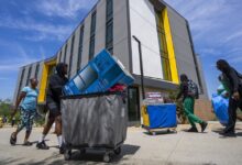 Students pushing carts in front of new housing