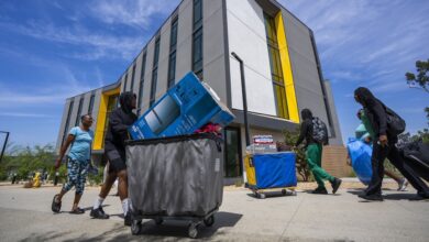 Students pushing carts in front of new housing