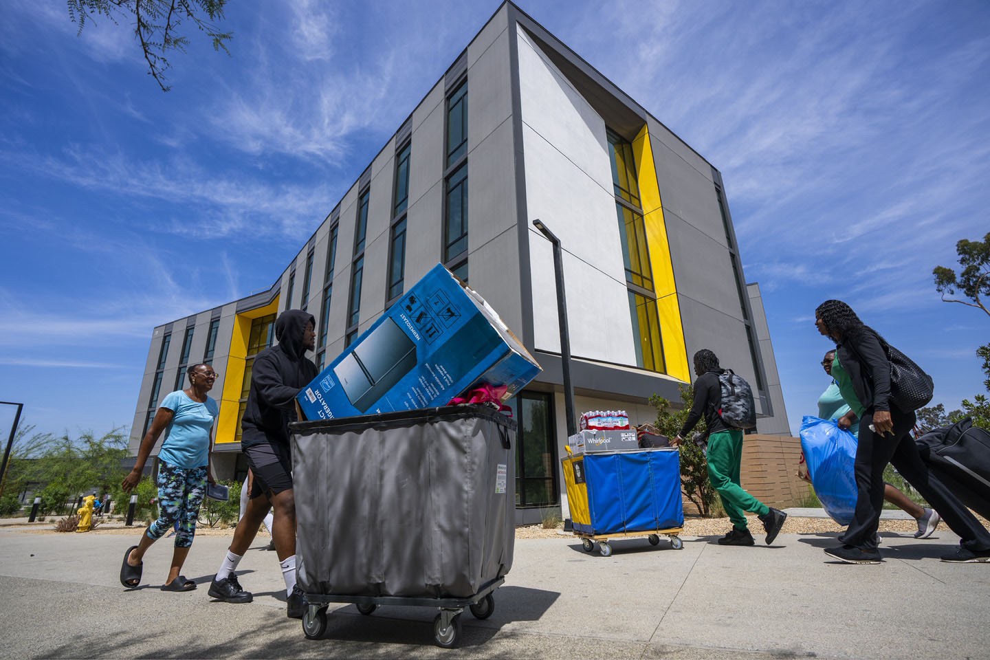 Students and parents push carts full of belongings into a residence hall.