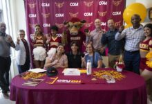 CSUDH and AEG representatives in front of CSUDH/CCAA signage at signing event.