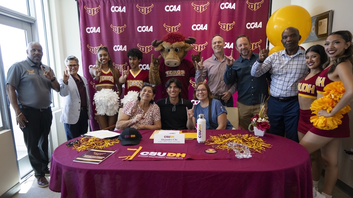 CSUDH and AEG representatives in front of CSUDH/CCAA signage at signing event.