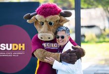 President Villarreal hugging Teddy Toro in front of a CSUDH sign